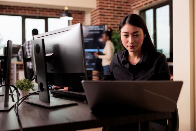 Woman working at her workstation checking network compliance for IT assessment